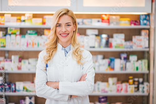 Portrait of a smiling pharmacist with arms crossed at modern pharmacy.
