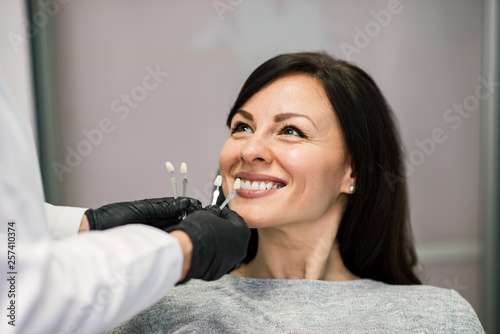 Headshot of smiling woman patient at dental clinic office.