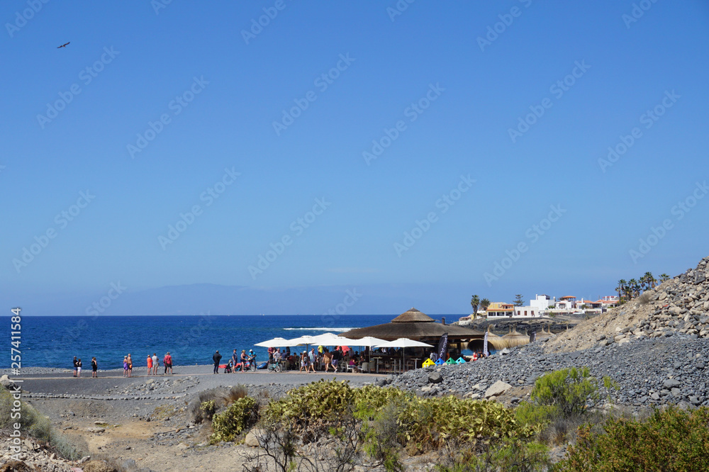 Beach bar from distance on the seacoast in La Caleta, Adeje, Tenerife, Canary Islands, Spain, seacoast, people