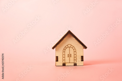 Miniature wooden house on a pink background close-up and copy space