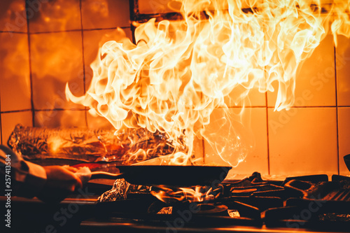 The chef cooking and makes a fire in a pan. Cooking with fire. Crown food. Charismatic chef in the kitchen.
