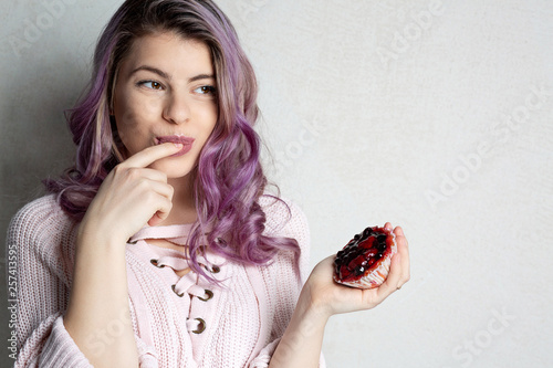 Cute young model with purple hair enjoying tasty dessert with berries. Space for text