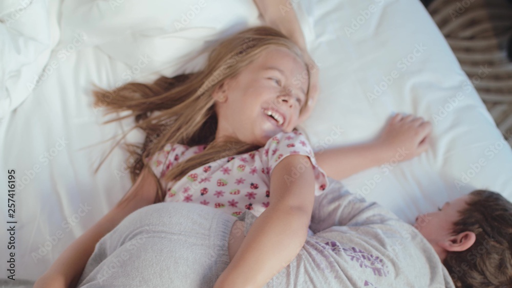 Happy Children Jump In Their Parent's Bed In The Morning Happy Children Jump In Their Parent's Bed In The Morning