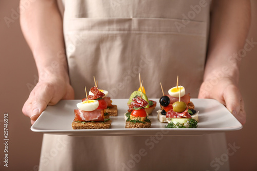 Fotografiet Woman holding plate with tasty canapes, closeup
