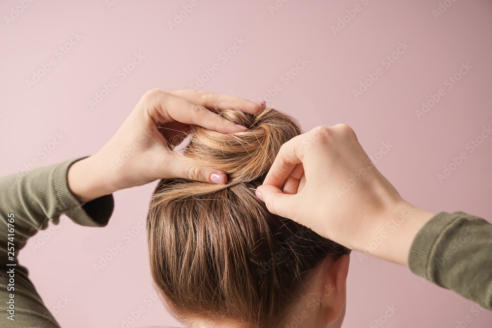 Fototapeta premium Young woman doing hair on color background