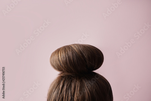 Young woman with hair bun on color background photo