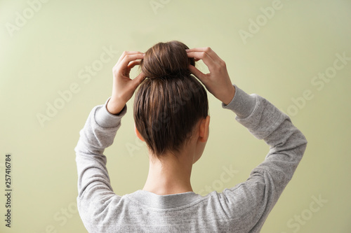 Young woman with hair bun on color background