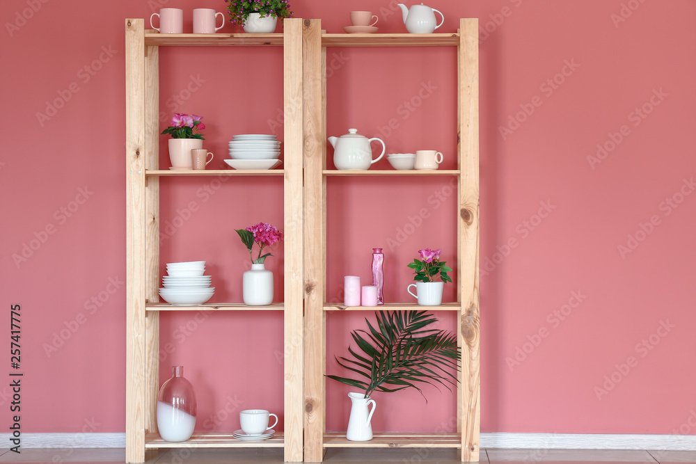 Wooden rack with clean dishes near color wall in kitchen
