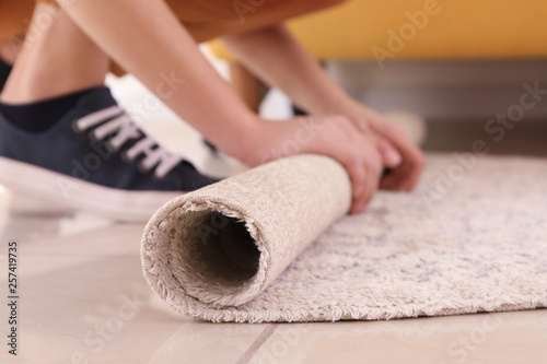Woman rolling carpet at home