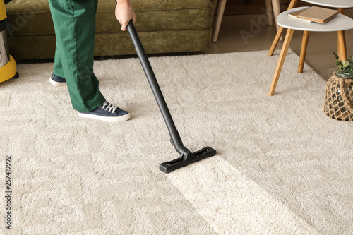 Worker cleaning carpet with hoover