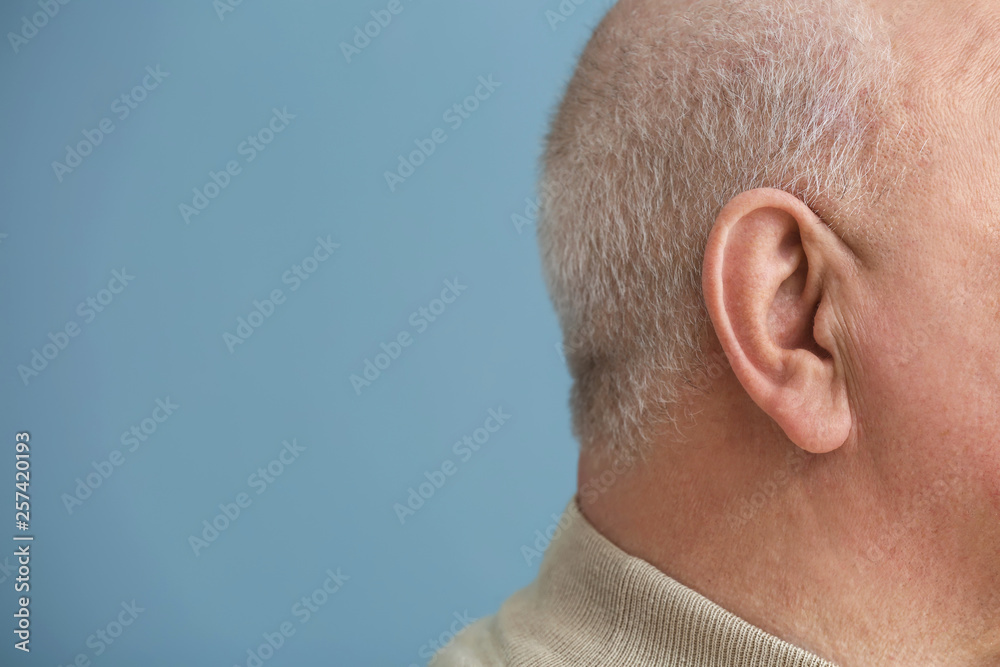 Obraz premium Senior man with hearing problem on color background, closeup