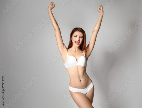 Beautiful young woman in underwear on grey background