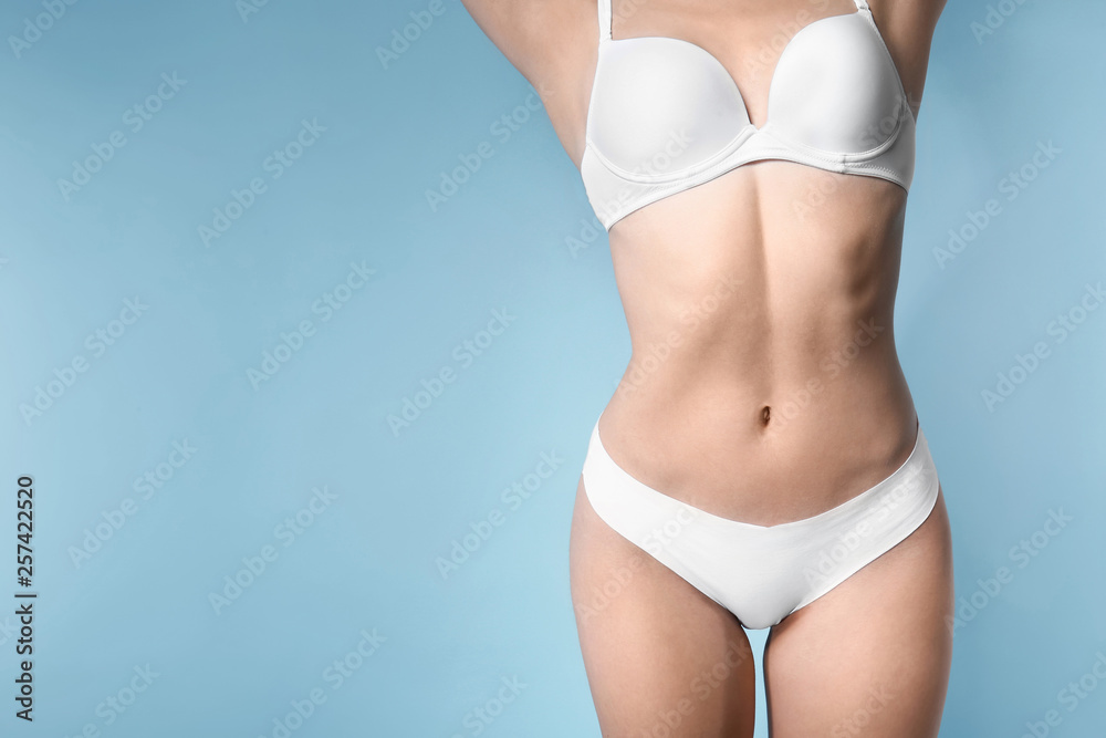 Beautiful young woman in white underwear on color background
