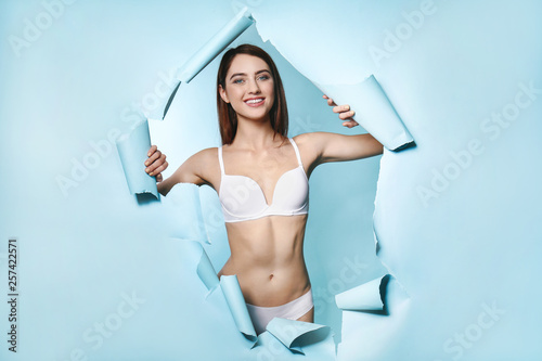 Beautiful young woman tearing color paper