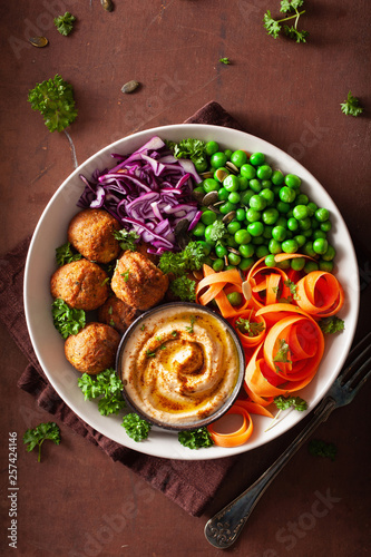 healthy vegan lunch bowl with falafel hummus carrot ribbons cabbage and peas