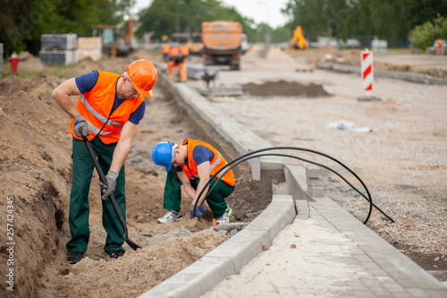 Two workers in orange safety jacket on a road construction, industry and teamwork