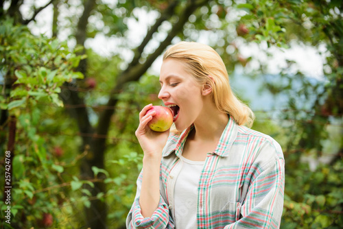 Healthy lifestyle. Eat fruits every day. Woman hold apple green garden background. Organic natural product. Girl gather apple harvest in own garden. Farmer girl hold apple. Local crops concept