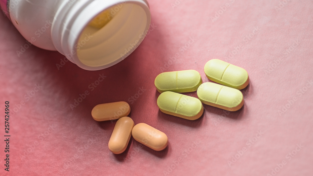 White, green, pink, orange capsules pill spilled out from white plastic bottle container. Global healthcare concept. Antibiotics drug resistance. Antimicrobial capsule pills and thermometer. Pharmaceu White, green, pink, orange capsules pill spilled out from white plastic bottle container. Global healthcare concept. Antibiotics drug resistance. Antimicrobial capsule pills and thermometer. Pharmaceu