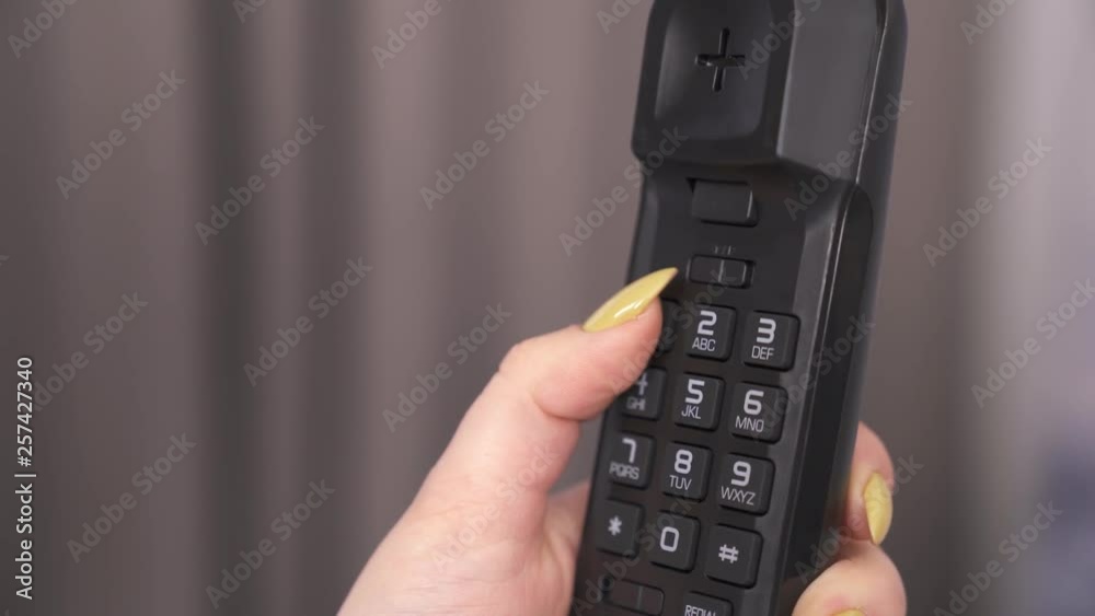 A close-up of female hand holding handset buttons phone and dealing a phone number A close-up of female hand holding handset buttons phone and dealing a phone number