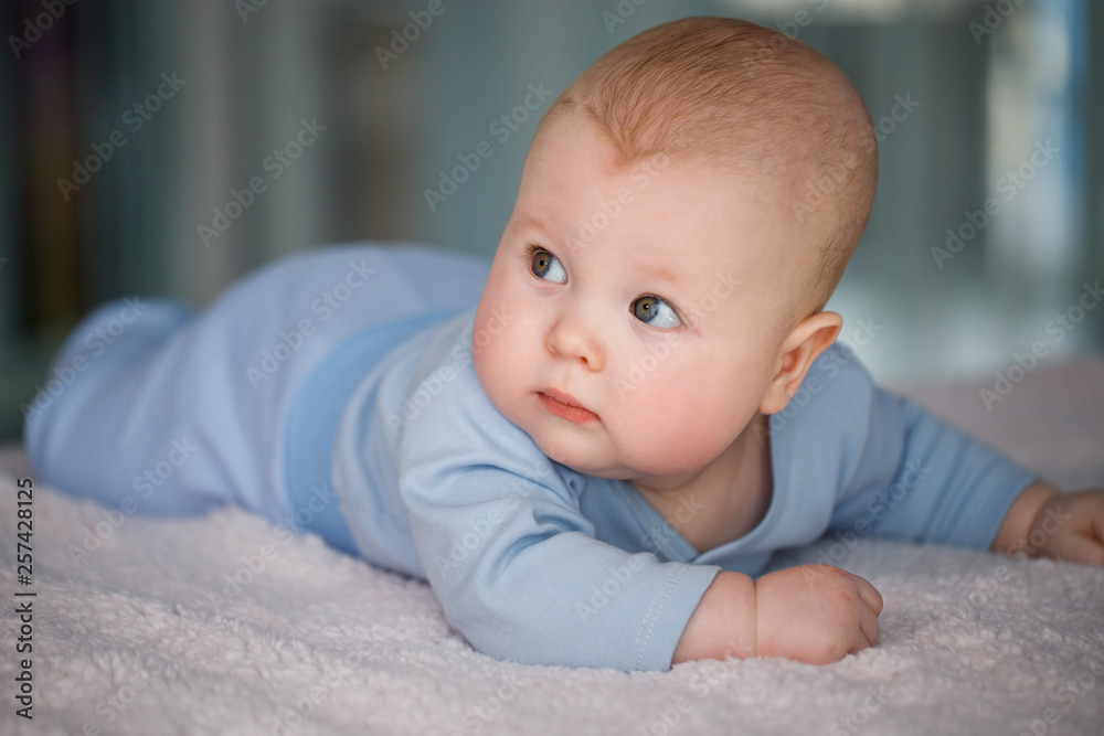 Portrait of a baby boy who lies on his stomach in a blue suit