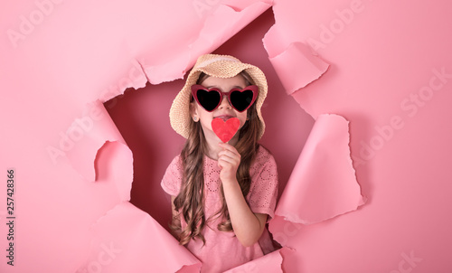 funny little girl with a heart on a stick on a colored background