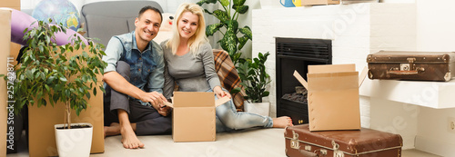 Young couple on the floor after moving into a new home with boxes around them.