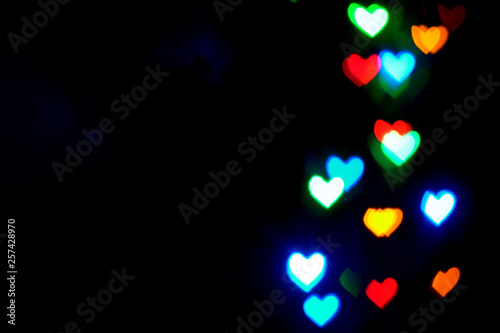 Multi colored blurred lights in the shape of hearts in the dark.
