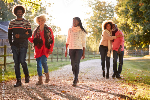 Senior Parents With Adult Offspring Enjoying Autumn Walk In Countryside Together