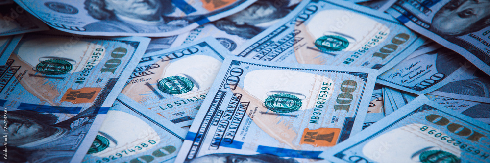 Obraz premium Background from dollars. Notes of one hundred American dollars are scattered across the background.