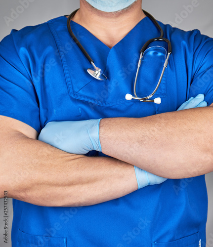 doctor in blue uniform and latex gloves crossed his arms over his chest