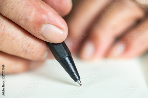 Senior man's hand writing letter on ivory colour paper, notebook, A black pen, Close up & Macro shot, Selective focus, Stationery concept
