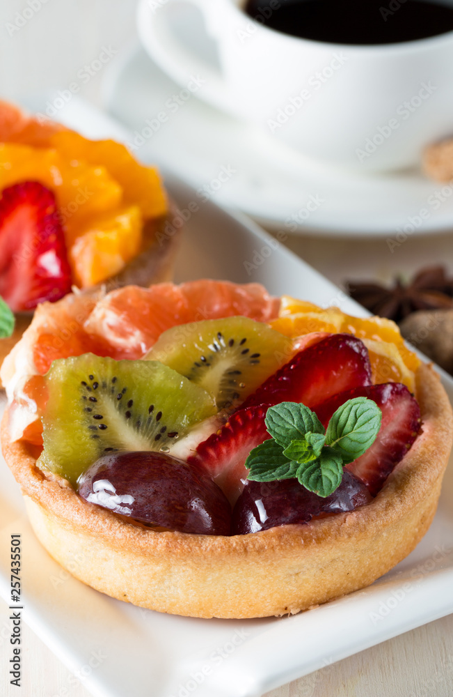 Fresh fruit and berry tart dessert with toss sugar on wooden background. Delicious sweet cake with raspberries, grapes, strawberries, cherry, kiwi, grapefruit and cream. Fresh fruit and berry tart dessert with toss sugar on wooden background. Delicious sweet cake with raspberries, grapes, strawberries, cherry, kiwi, grapefruit and cream.