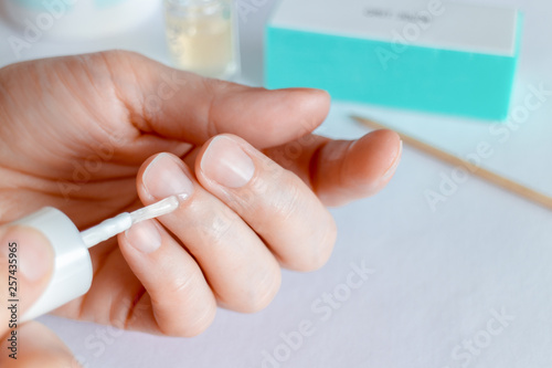 Woman doing at-home manicure, applying oil on cuticles.