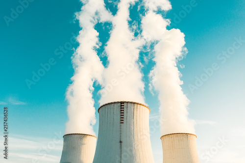 A Power plant with white smoke over it's chimneys
