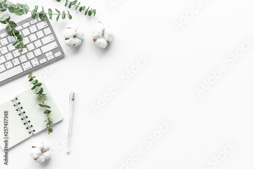 Laptop, cotton branch on white table flat lay copy space. Minimal freelancer home office desk workspace.