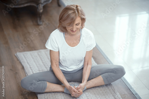 A Woman Over the Age of 50 is Doing Yoga at Home.