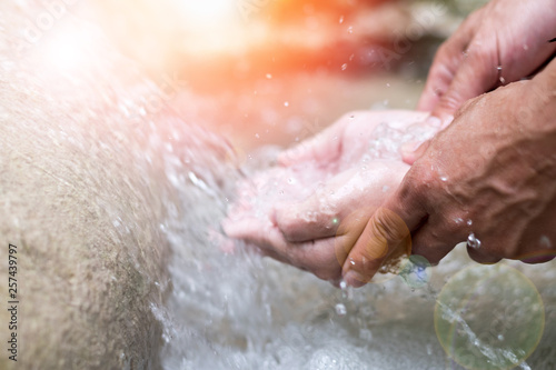 Father's hand hold daughter hands to save water at waterfall. National Water Quality Month.