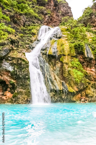 Fototapeta Naklejka Na Ścianę i Meble -  Waterfall in Ayn Khor  and Lush green landscape, trees and foggy mountains at tourist resort, Salalah, Oman