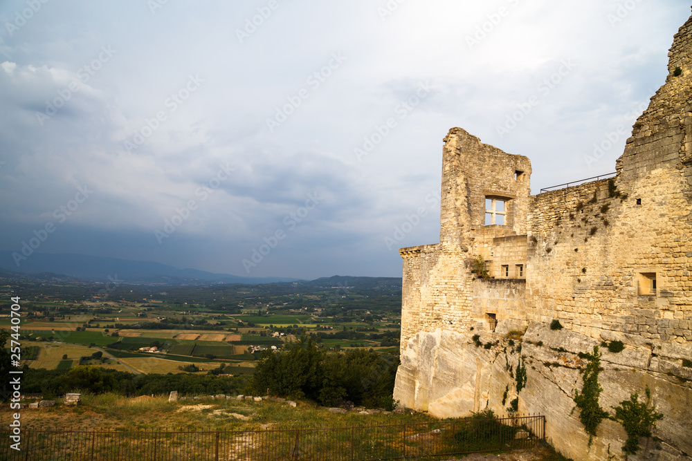 Old ruined stone walls with a window of the Castle of Marquis de Sade in Lacoste, Provence, France. Provence countryside in the background.