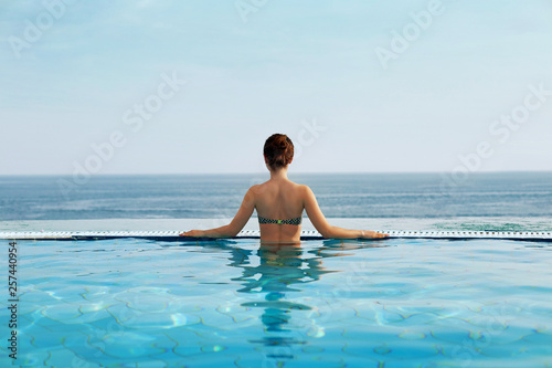 Portrait woman relax luxury pool villa, infinity sea view, copy space.
