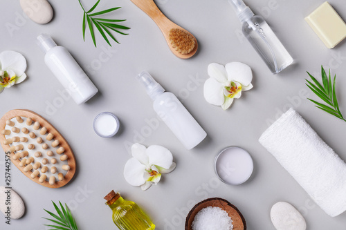 Spa, aromatherapy, beauty treatment and wellness background with massage brush, towel, orchid flowers and cosmetic products. Top view and flat lay.
