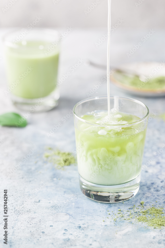 Iced Matcha green latte in glasses with matcha powder on light background. Iced Matcha green latte in glasses with matcha powder on light background.