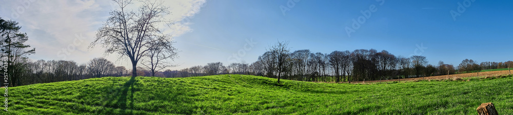 breites Landschaftspanorama mit grüner Wiesen und blauem Himmel. Lohmar, NRW, Deutschland. Frühlingsbeginn. breites Landschaftspanorama mit grüner Wiesen und blauem Himmel. Lohmar, NRW, Deutschland. Frühlingsbeginn.