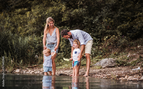 Young family with two toddler children outdoors by the river in summer, playing. photo