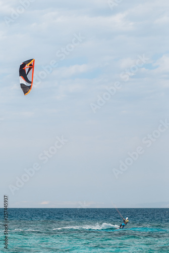 professional kiter glide the water surface of the ocean at great speed. Back view behind extreme wide shot