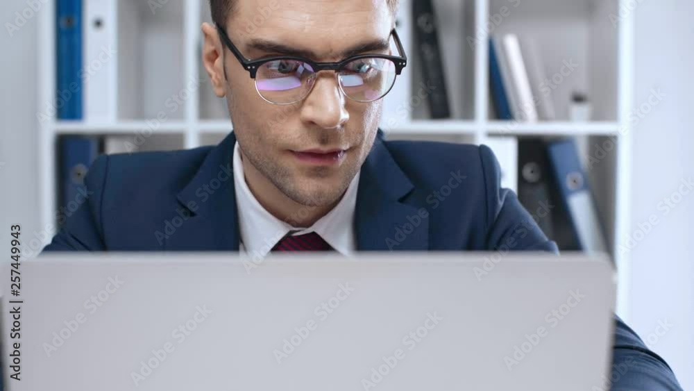 handsome, attentive businessman in eyeglasses using laptop in office handsome, attentive businessman in eyeglasses using laptop in office