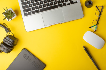 Top view of the workplace designer. Creative designer, graphics tablet, laptop, and accessories for the graphic designer.Flat lay.On yellow background
