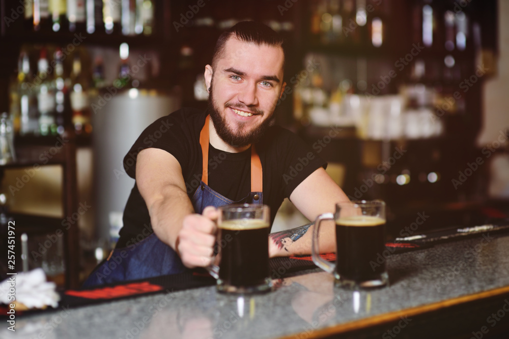 young cute barman with a mug of beer smiling at the bar background. Oktoberfest