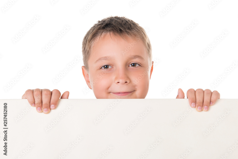 Smiling handsome boy male teenager posing behind white panel on white background. Advertising space for billboard poster Smiling handsome boy male teenager posing behind white panel on white background. Advertising space for billboard poster