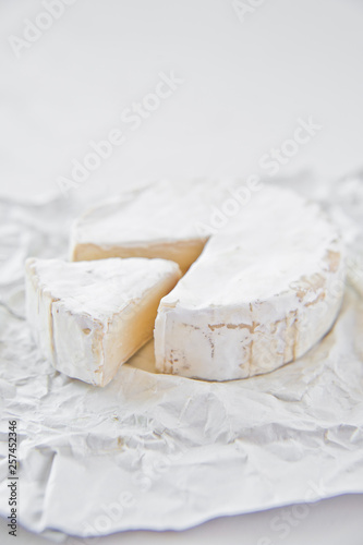 Brie cheese on white paper. White background, side view, close-up